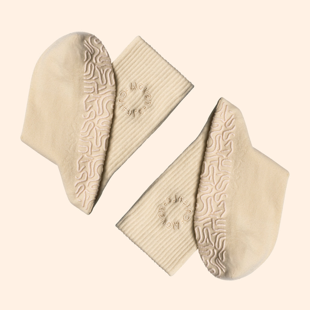 Beige organic cotton socks with grip insoles with textured patterns on a light beige background