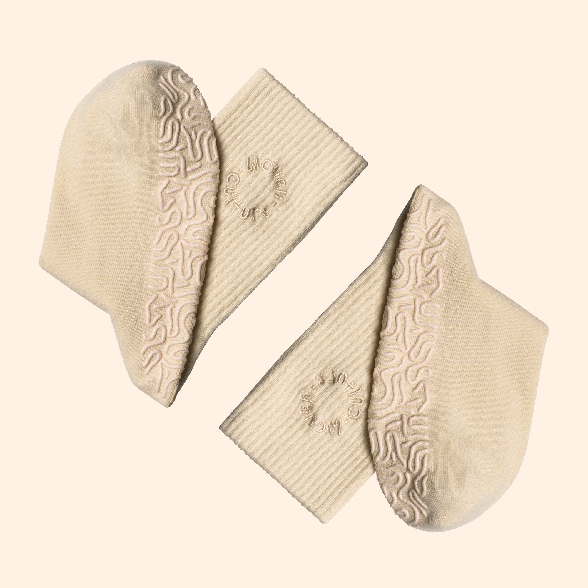 Beige organic cotton socks with grip insoles with textured patterns on a light beige background