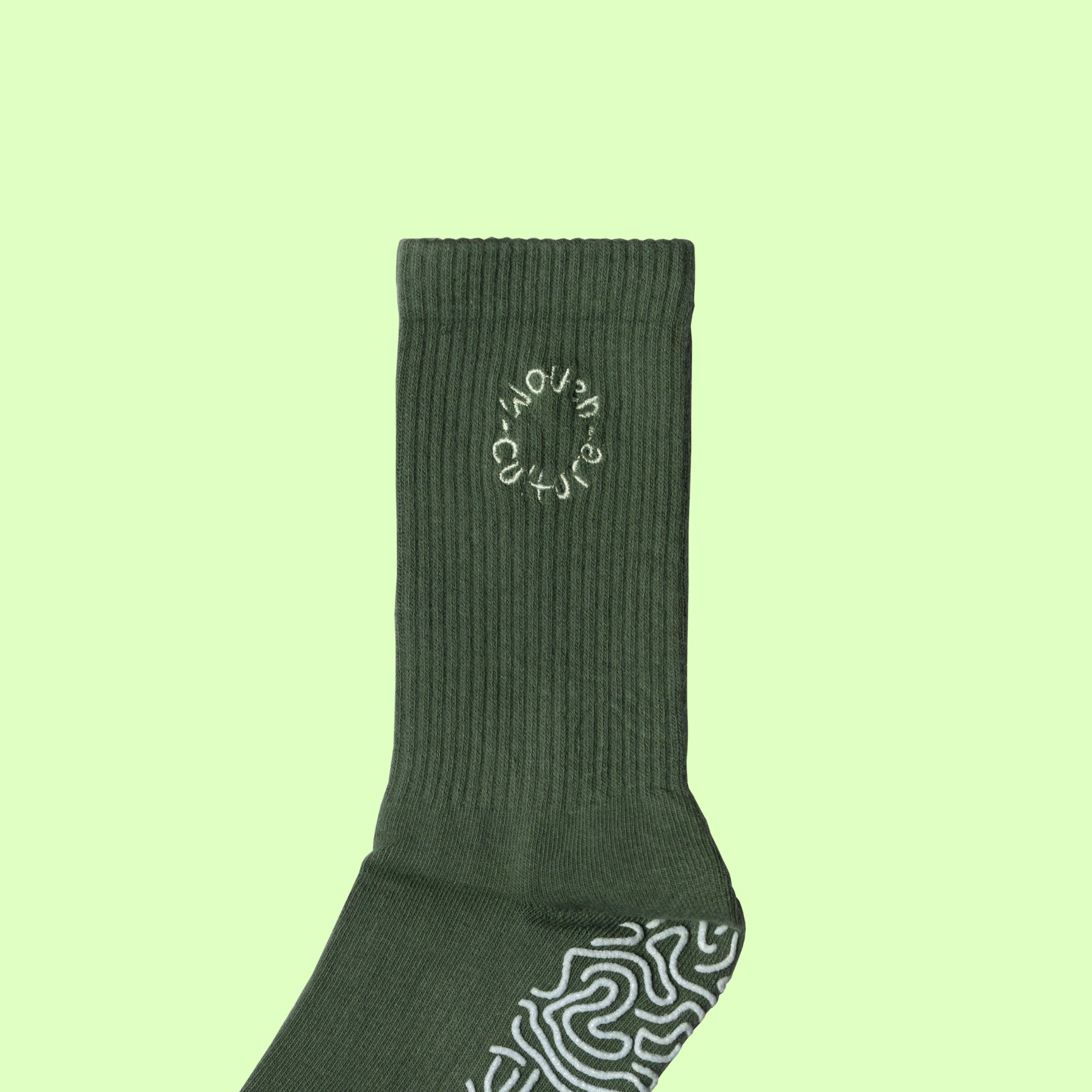 Close-up of olive green Woven Culture organic grip sock with ribbed cuff and embroidered logo for Pilates and yoga.